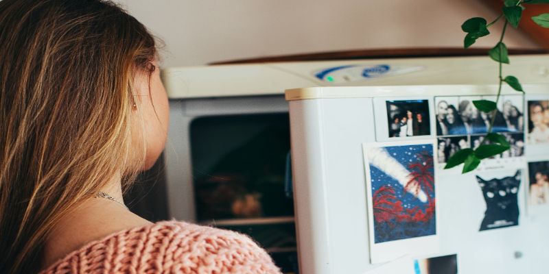 Mujer enfrente de refrigerador con la puerta abierta